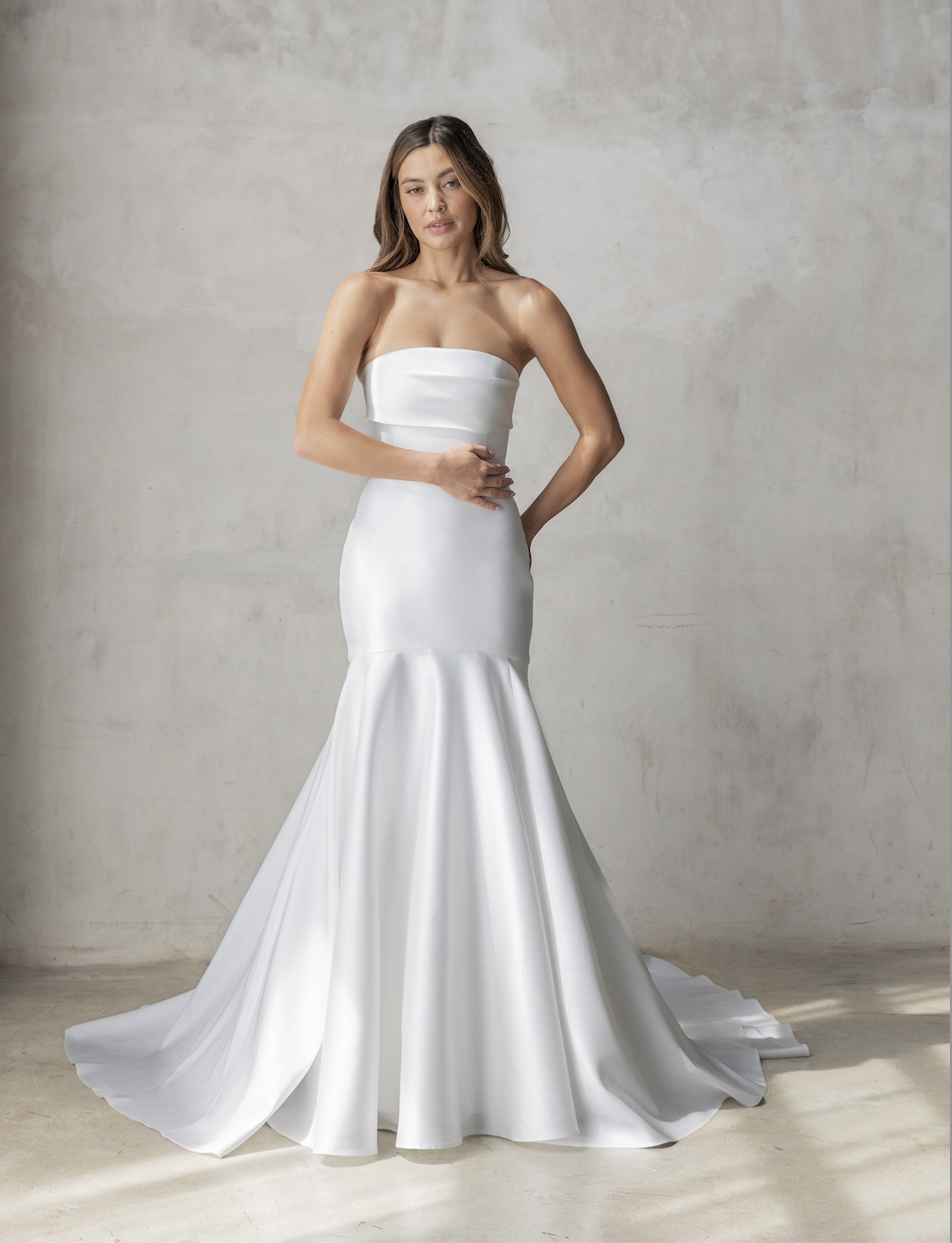 Model is wearing a strapless fit-and-flare gown in Spanish mikado with a sculpted bodice and dramatic mermaid skirt.