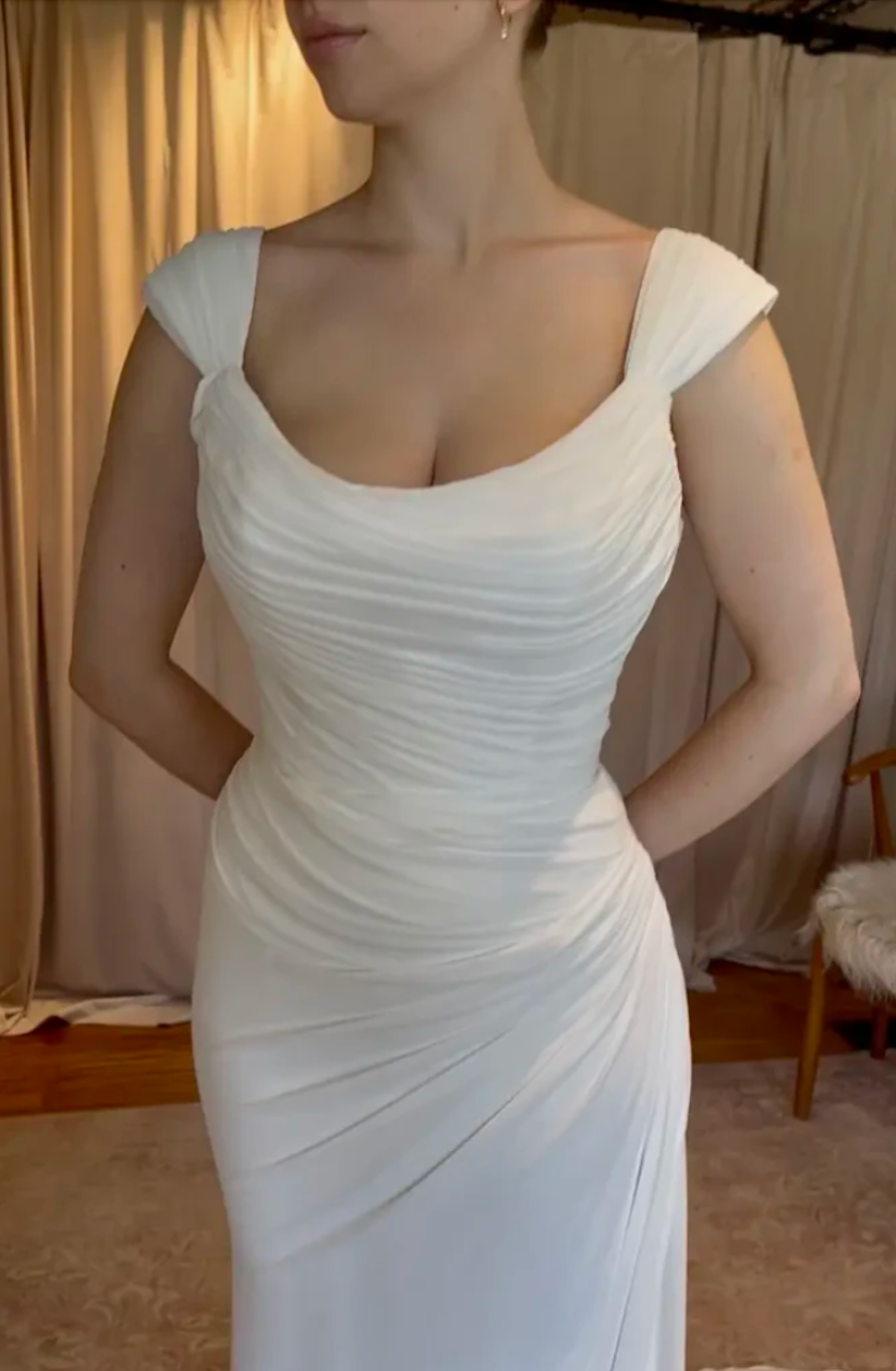 Model is wearing a chiffon gown with cap sleeves, romantic ruching on the bodice, and a fitted silhouette designed for movement.